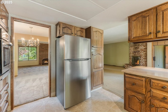 324 N Peacock Ct, Newberg, OR 97132 - kitchen featuring stainless steel appliances, a fireplace, light colored carpet, and brown cabinets