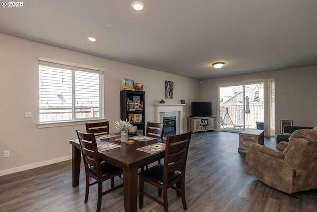 dining area with dark wood-type flooring, recessed lighting, baseboards, and a glass covered fireplace