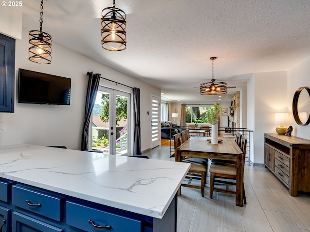 5210 N Emerson Dr, Portland, OR 97217 - kitchen with blue cabinets, plenty of natural light, a peninsula, open floor plan, and a textured ceiling