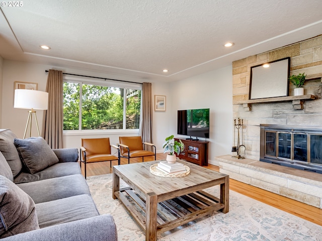 5210 N Emerson Dr, Portland, OR 97217 - living room featuring light wood finished floors, a stone fireplace, recessed lighting, a textured ceiling, and baseboards