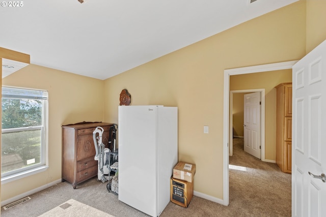 bedroom featuring light carpet and white refrigerator