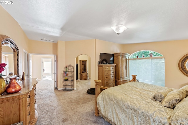 bedroom with light colored carpet and a textured ceiling