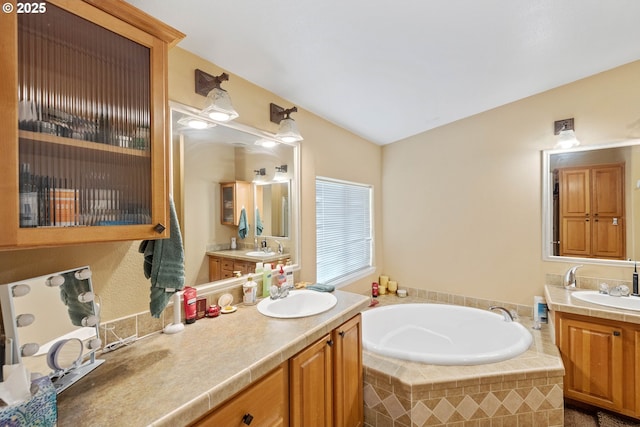 bathroom featuring tiled tub and vanity