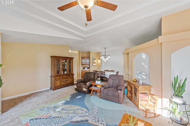 living room featuring a raised ceiling, ceiling fan with notable chandelier, and light carpet