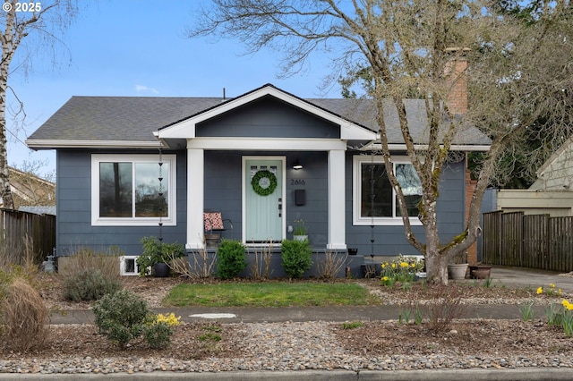 bungalow-style home featuring a porch, fence, and a shingled roof