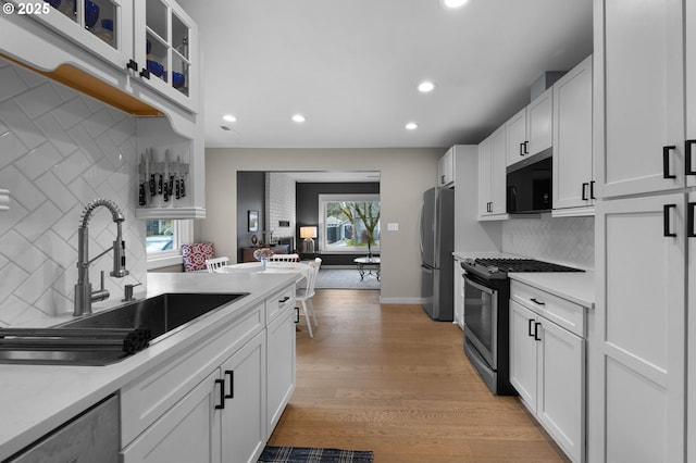 kitchen with a sink, appliances with stainless steel finishes, white cabinets, and light countertops