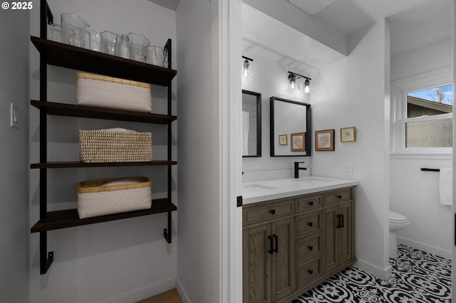 full bathroom with double vanity, toilet, baseboards, and a sink