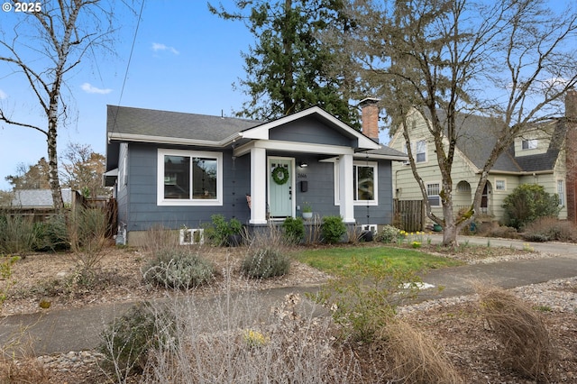 bungalow-style home featuring a chimney and a shingled roof