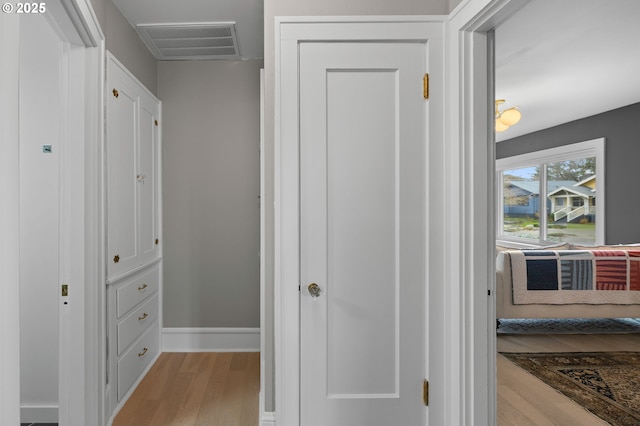 hallway featuring visible vents, baseboards, and wood finished floors