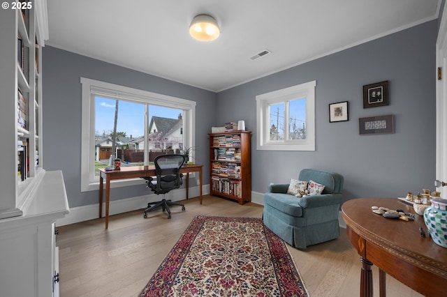 office space with baseboards, a healthy amount of sunlight, light wood-style floors, and ornamental molding