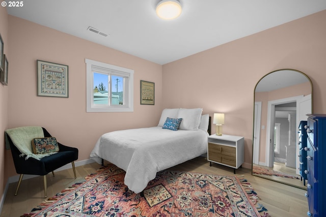 bedroom with visible vents, baseboards, and light wood finished floors