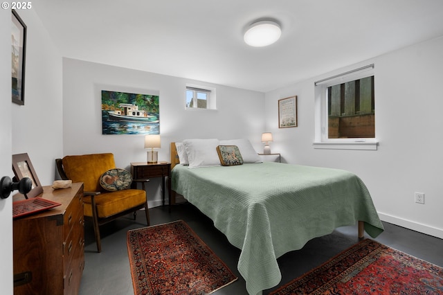 bedroom with finished concrete floors and baseboards