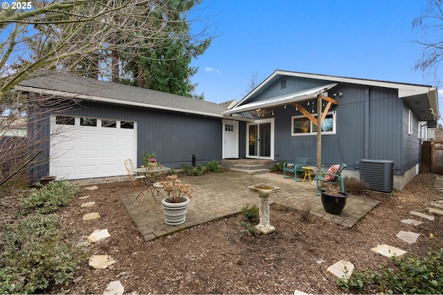 single story home featuring a garage, central AC unit, and a patio area