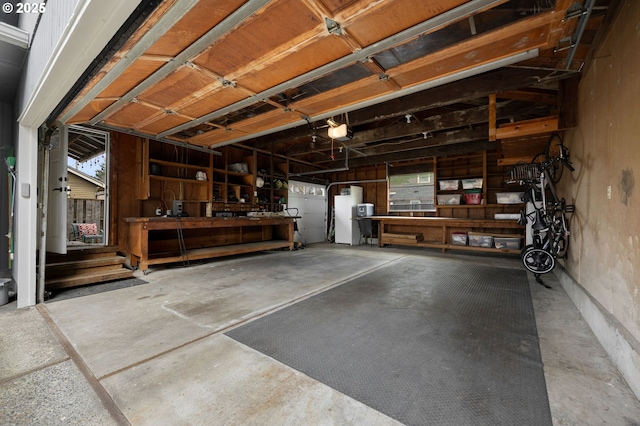 garage with freestanding refrigerator, a workshop area, water heater, and a garage door opener