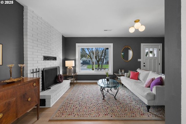 living area featuring a fireplace, plenty of natural light, wood finished floors, and baseboards