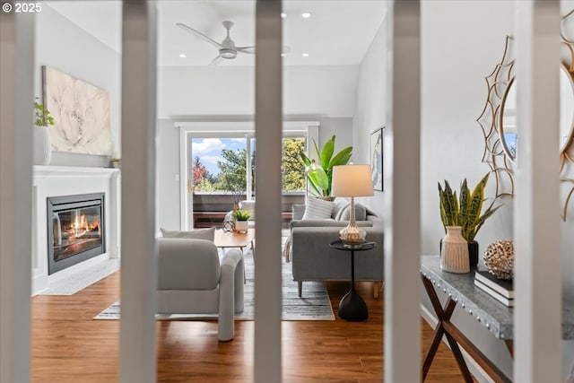 interior space featuring a ceiling fan, a glass covered fireplace, wood finished floors, and recessed lighting