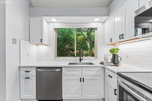 kitchen with white cabinets, dishwasher, light countertops, and a sink