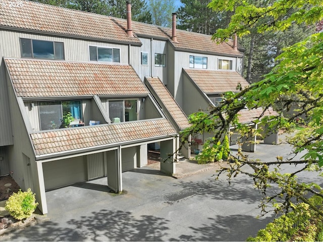 back of property with driveway and a tiled roof