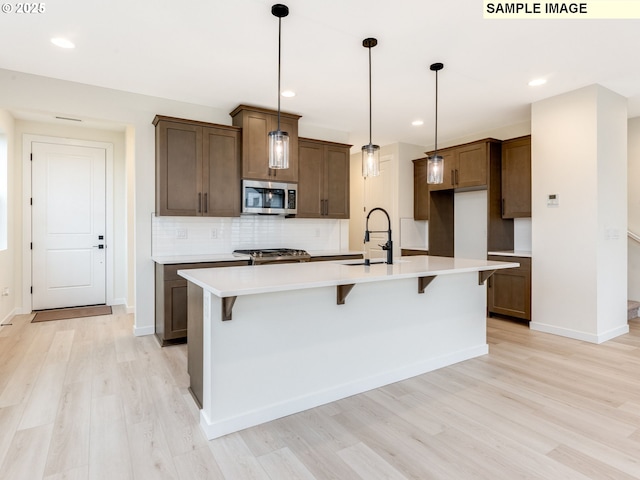 kitchen with tasteful backsplash, light wood-style flooring, stainless steel appliances, and light countertops