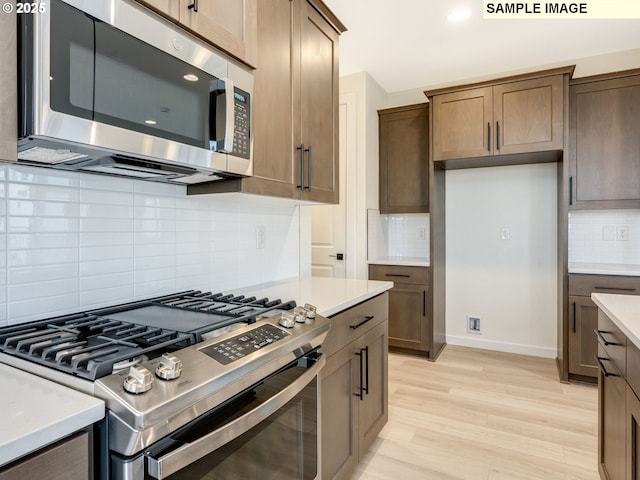 kitchen featuring stainless steel appliances, baseboards, light wood-style flooring, and light countertops