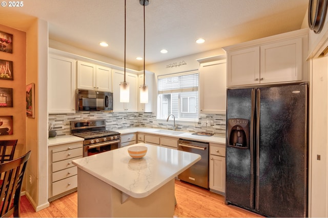 kitchen with sink, a center island, white cabinetry, pendant lighting, and black appliances