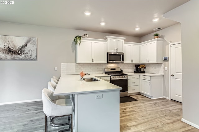 7897 SW Mara Ct, Portland, OR 97224 - kitchen featuring stainless steel appliances, a sink, a peninsula, a breakfast bar, and light countertops