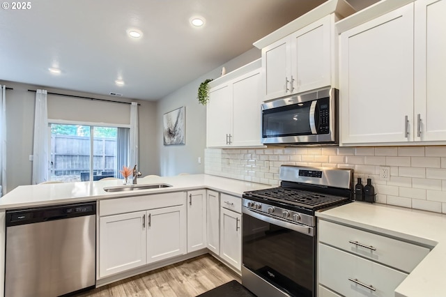 7897 SW Mara Ct, Portland, OR 97224 - kitchen with stainless steel appliances, a sink, light countertops, a peninsula, and light wood-style flooring