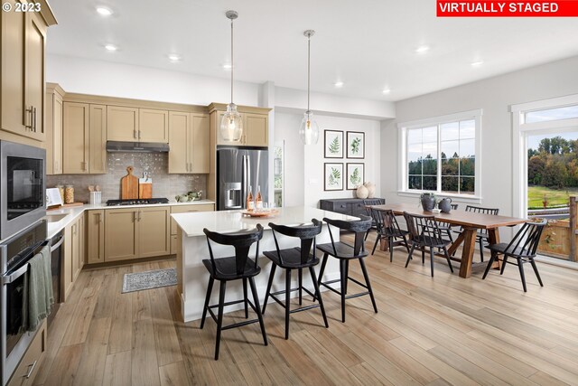 kitchen with built in microwave, sink, a center island, hanging light fixtures, and stainless steel refrigerator