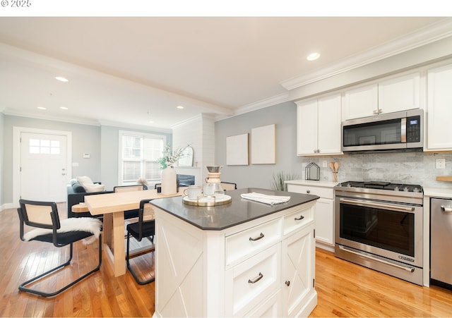 621 NE Randall Ave, Portland, OR 97232 - kitchen with appliances with stainless steel finishes, crown molding, light wood-style flooring, backsplash, and recessed lighting