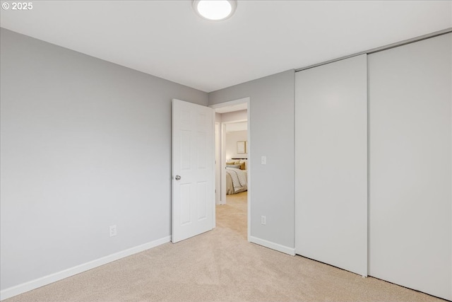 unfurnished bedroom with baseboards, a closet, and light colored carpet