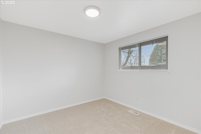 spare room with light colored carpet, visible vents, and baseboards