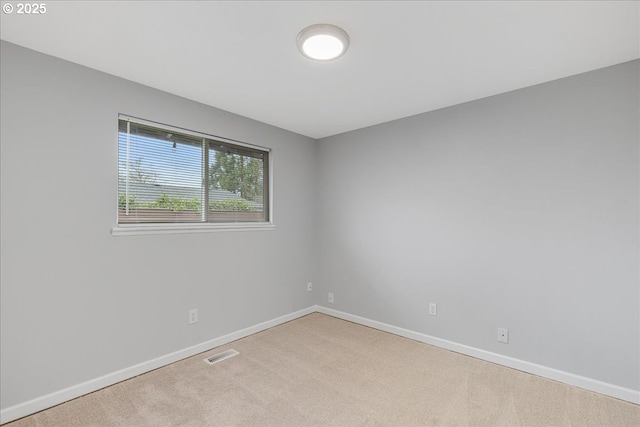 carpeted spare room featuring visible vents and baseboards