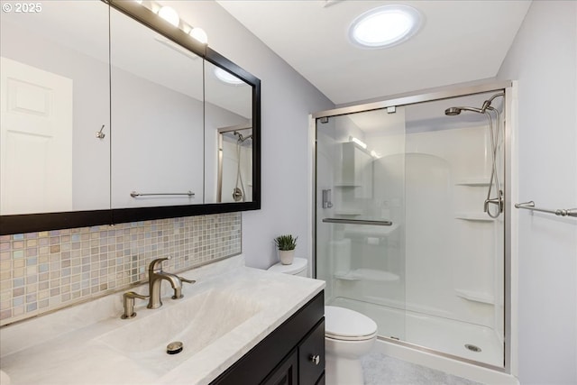 bathroom with toilet, a shower stall, decorative backsplash, and vanity