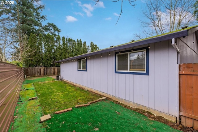 view of home's exterior with central air condition unit, a fenced backyard, and a yard