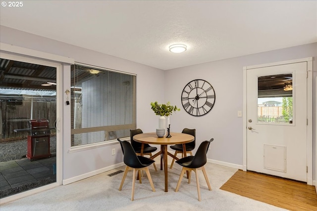 dining space featuring light carpet, visible vents, baseboards, and a textured ceiling