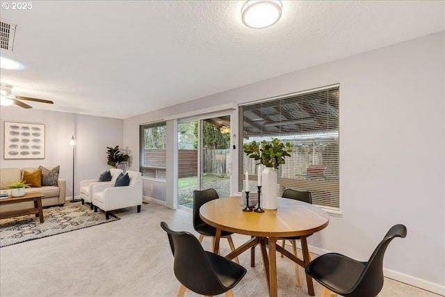 dining area featuring baseboards, a textured ceiling, a ceiling fan, and light colored carpet