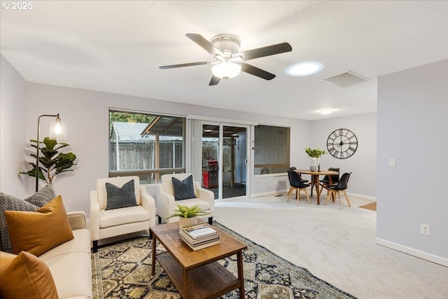 carpeted living area with ceiling fan, a textured ceiling, visible vents, and baseboards