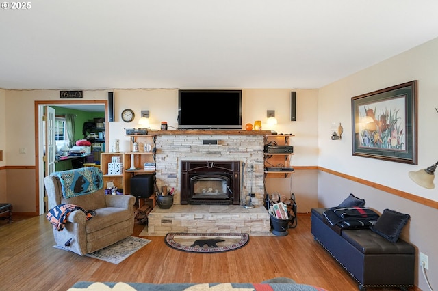 living room with a stone fireplace and hardwood / wood-style floors