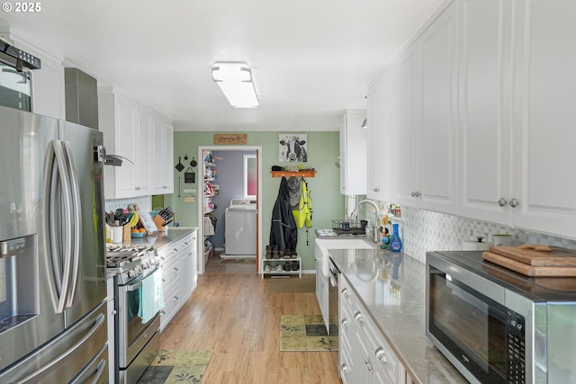 kitchen featuring backsplash, washer / dryer, light wood-type flooring, stainless steel appliances, and white cabinets