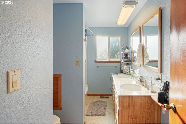 bathroom with tile patterned floors, vanity, toilet, and walk in shower