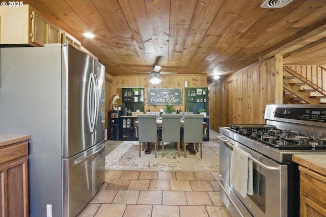 33712 Rainbows End Ln, Warrenton, OR 97146 - kitchen featuring appliances with stainless steel finishes, wood ceiling, wood walls, light stone finish floors, and light countertops