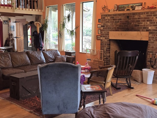 living room with wood-type flooring, plenty of natural light, and a brick fireplace