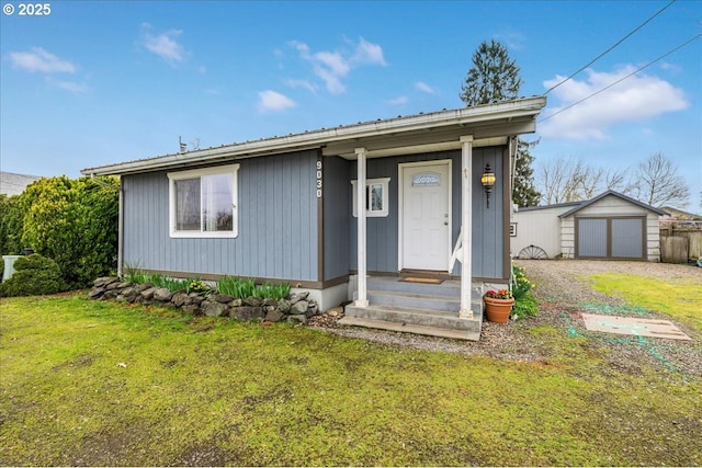 view of front of house featuring gravel driveway, a front yard, an outbuilding, and a garage