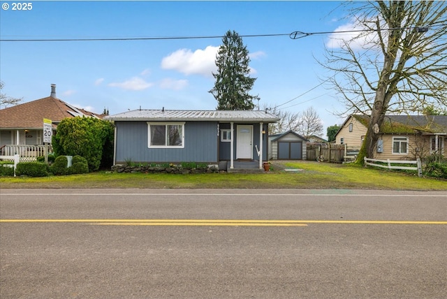 view of front of house with an outbuilding, a garage, fence, a front yard, and metal roof