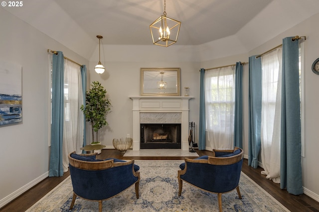 living room featuring wood finished floors, a chandelier, a premium fireplace, and baseboards