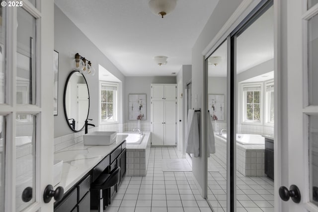 full bath featuring tile patterned floors, a bath, and double vanity