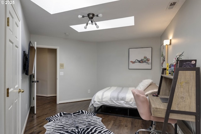bedroom featuring a skylight, wood finished floors, and baseboards
