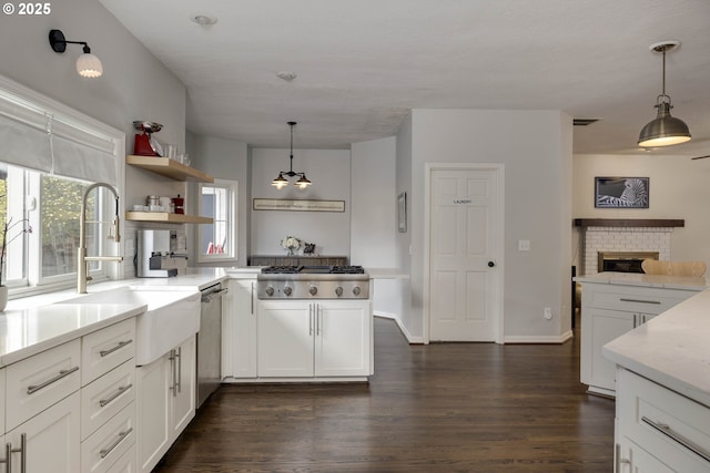 kitchen with appliances with stainless steel finishes, a sink, dark wood-type flooring, and hanging light fixtures