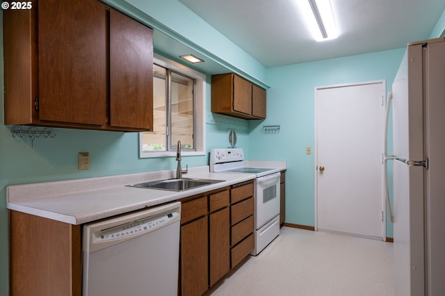 kitchen featuring white appliances, light floors, a sink, light countertops, and brown cabinets