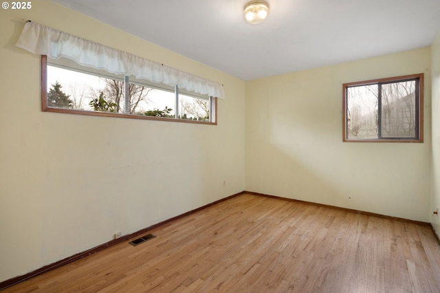 empty room featuring visible vents, baseboards, and wood finished floors